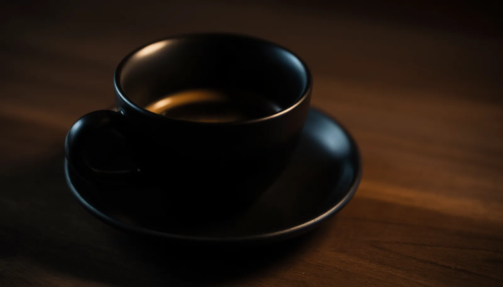 Black coffee in a hand-thrown porcelain cup, lit from one side