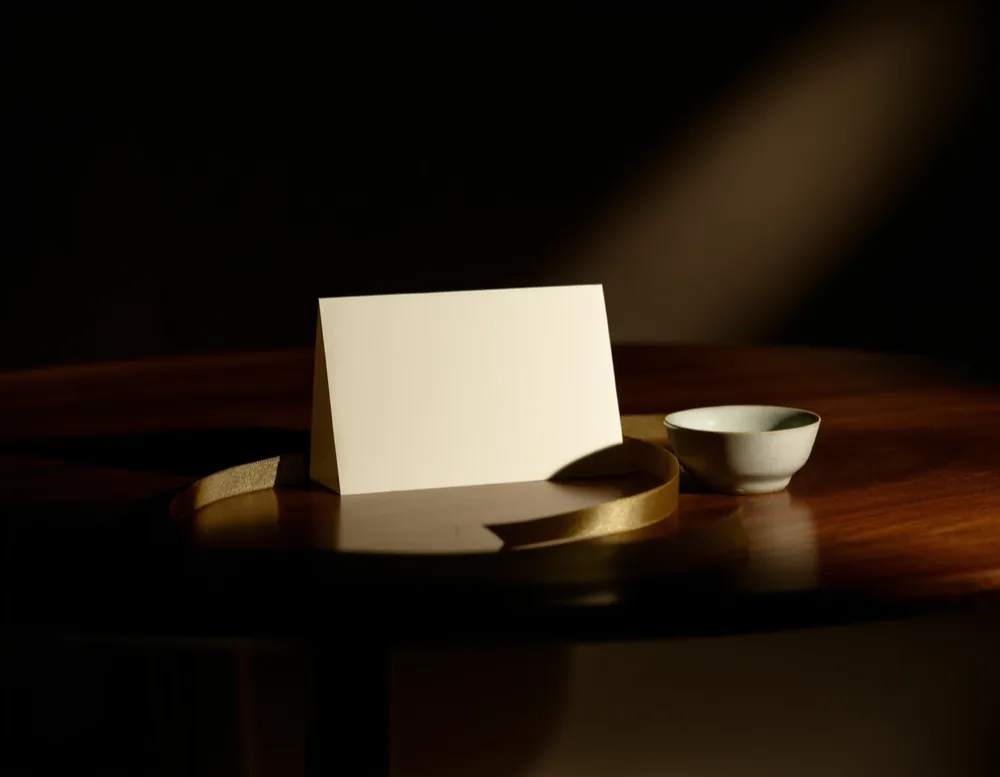 A blank cream card and a length of brass-coloured ribbon on dark walnut